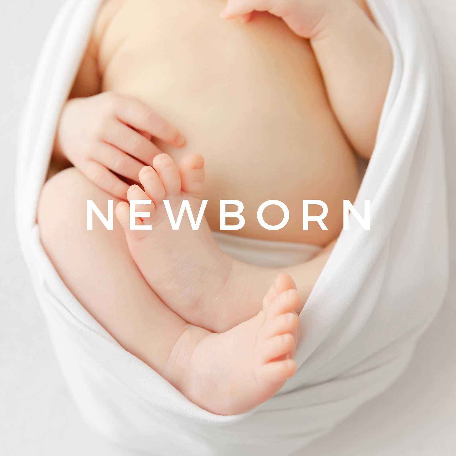 Newborn baby legs folded up in a white blanket