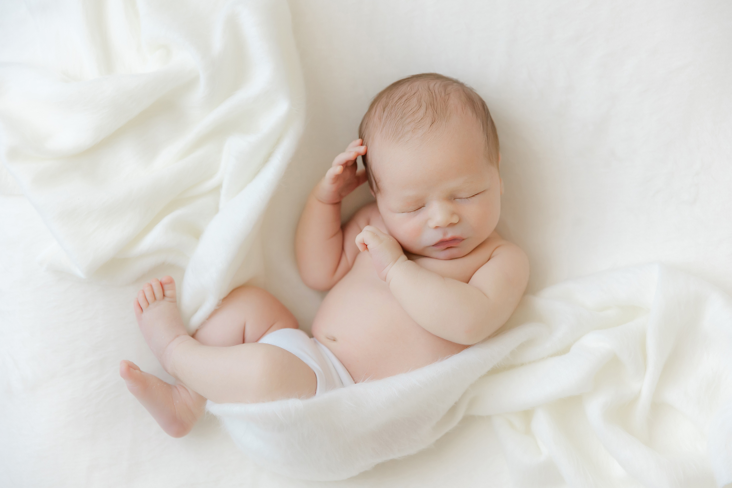 Newborn baby lays peacefully wrapped gently in a white swaddle